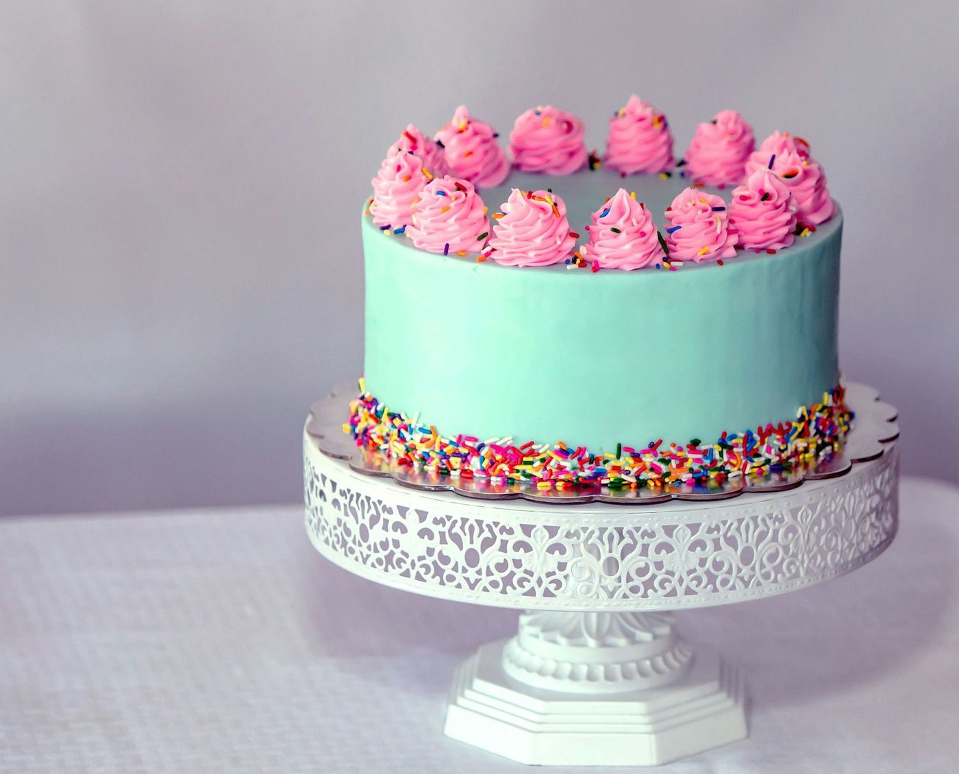 Frosted celebration cake on a white cake stand